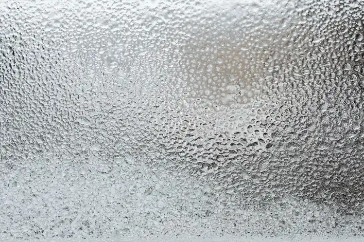 Escarcha y gotas de hielo en primer plano sobre una superficie de cristal fría