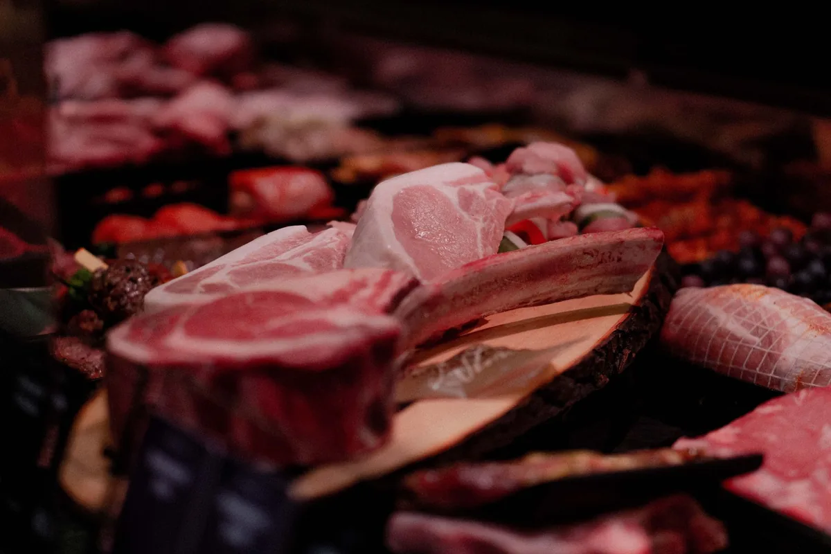 Cortes de carne fresca de cerdo sobre una tabla redonda de madera en un expositor