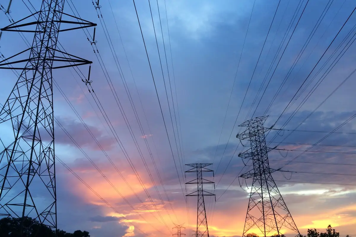 Torres de alta tensión y cables contra un cielo de atardecer