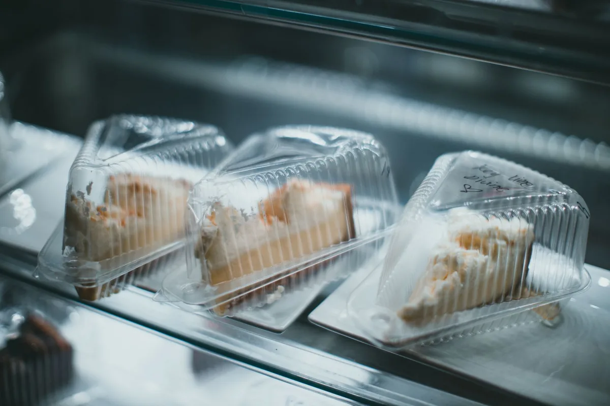 Tres porciones de tarta en envases de plástico dentro de una vitrina refrigerada